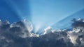 Sun rays behind dark clouds in a blue sky Royalty Free Stock Photo