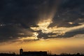 Sun Rays Break Through the Clouds Over the Silhouette Church at Sunset Royalty Free Stock Photo