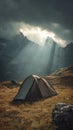 Sun rays breaking through dark clouds onto a tent in a serene mountain valley Royalty Free Stock Photo