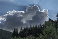 Sun rays coming from under the dark storm clouds above the black forest and roofs of houses Royalty Free Stock Photo