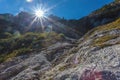 Sun rays filter between the Dolomite peaks over waterfall in Comelico Region