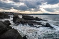 Sun rays through heavy clouds over Ships Rock formation in Sinemorets