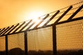 Sun rays over barb wire on metal fence, Sunset Royalty Free Stock Photo