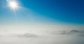 Sun rays shining in the blue sky above white and fluffy clouds Royalty Free Stock Photo