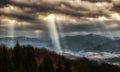 Sun rays shining through dark clouds on the hills Royalty Free Stock Photo