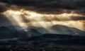 Sun rays shining through dark clouds on the hills Royalty Free Stock Photo