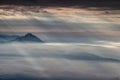 Sun rays shining through dark clouds illuminate conical peaks Royalty Free Stock Photo