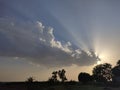 Sun rays spreading behind cloud at sunset Royalty Free Stock Photo