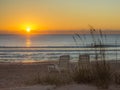 Sun Rise Glowing on Smooth Sea with Empty Chairs Royalty Free Stock Photo