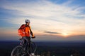 Sun rises behind man getting ready to ride his road bike on lonely paved highway during summer. Includes copy space.