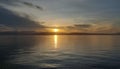 The sun rises over the mountains with its reflection in the calm sea water Royalty Free Stock Photo