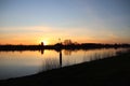 The sun rises over the water of the river Hollandsche IJssel near the dike at Park Hitland