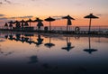 The sun rises by the pool near the hotel in Mallorca. Sun umbrellas reflected in the water Royalty Free Stock Photo