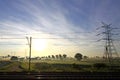 Sun rising behind electricity pylon