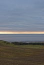 The sun rising beneath the Low Cloud layer over Lunan bay and the rolling Farmland behind the beach.