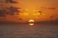 The sun rising with clouds going through center on ocean.