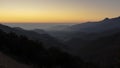 Sun rising on a foggy dark mountain range silhouette