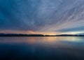 The sun rising over a lake with the colors of sunrise reflecting off the clouds and the water Royalty Free Stock Photo