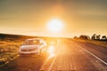 Sun Rising Over VW Volkswagen Polo Vento Sedan Car Parking Near Asphalt Country Road In Sunny Morning Or Evening. Open Royalty Free Stock Photo