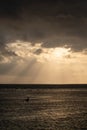 The sun`s rays over the sea, burst out of the cloud. Dramatic sunset on the sea, beautiful peaceful scene, rays of light shine in Royalty Free Stock Photo