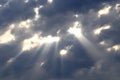 The sun's rays pass through cracks, holes in gray storm clouds. Rainy, cloudy weather. The sun appears behind the clouds