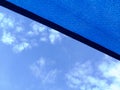 Sun sail. loosely weaved blue fabric sun shade material spanning over terrace area. blue sky and cluds