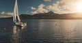 Sun sailboat at ocean bay water reflection aerial. Summer cruise at green mountains island of Arran