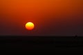 The sun sets over the horizon in the desert Royalty Free Stock Photo