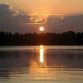 Sun sets over lake, casting golden reflections on water Royalty Free Stock Photo