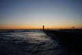 the sun is setting behind a lighthouse on the water near shore Royalty Free Stock Photo