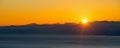 The sun setting behind the mountains in the clouds over the coast and the city Royalty Free Stock Photo