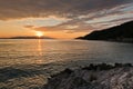 Sun is setting behind Skiathos island with some sea rocks in foreground at Kastani Mamma Mia beach, island of Skopelos