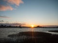 sun setting horizon blue water sky surface silhouette coast ocean waves Royalty Free Stock Photo