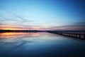 Sun setting with long jetty extending out in lake