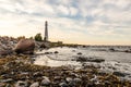 Sun is setting near lighthouse on the shore. Royalty Free Stock Photo