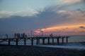 Sun setting over Batumi beach pier, as powerful waves roll in, and a very colorful sky is reflected on the beach