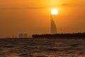 the sun is setting over a city on the horizon of the ocean with a boat in the foreground and a buliding in the distance
