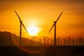 Sun Setting Over Electrical Power Lines and Wind Turbine Farm Silhouetted Against Polluted Desert Sky