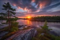 the sun is setting over a lake with rocks and trees in the foreground and a forest in the background with a few clouds in the sky Royalty Free Stock Photo