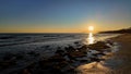 Sun setting over Marbella beach in Spain illuminating rocks and waves Royalty Free Stock Photo