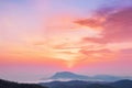 the sun is setting over a mountain range with a few clouds in the sky and a few hills in the foreground with a few trees in the Royalty Free Stock Photo