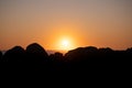 Sun setting over the ocean, behind large rocks in silhouette in foreground. Royalty Free Stock Photo