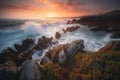 the sun is setting over the ocean with waves crashing on the rocks Royalty Free Stock Photo