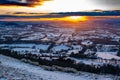 Sun setting over the snowy Cotswolds hills with sheep in the foreground