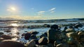 the sun is setting over the stone beach the reflections Pacific Ocean is very quiet and calm there are no waves relaxing Royalty Free Stock Photo