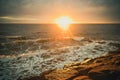 Sun setting over water with waves and rocks. Royalty Free Stock Photo