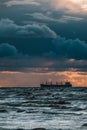 Sun setting at the sea with sailing cargo ship, scenic view. Clouds and storming sea. Defocused. Royalty Free Stock Photo