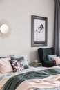 Sun shape like mirror and map in black frame on grey wall of fashionable bedroom interior with king size bed with cozy bedding