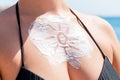 Sun shaped sunscreen on woman`s breast over sea background Royalty Free Stock Photo