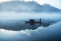 A fishman on the boat in the fog on the river, the golden cloud reflection on the surface of water,cold tone.